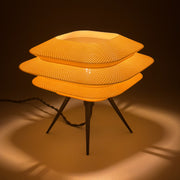 BLOC Bone lit on a pale surface, three stacked knit-textured tiers glowing warm above black tripod legs