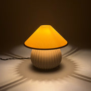 MIRO Bone lit on a soft pale surface, its pleated shade casting a scalloped ring of warm light