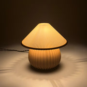 MIRO Caramel lit on a soft pale surface, its pleated shade casting a scalloped ring of warm light