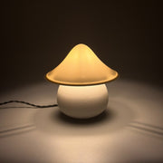 MOSS Ivory lit on a pale surface, its textured cream cap glowing warm above the rounded base